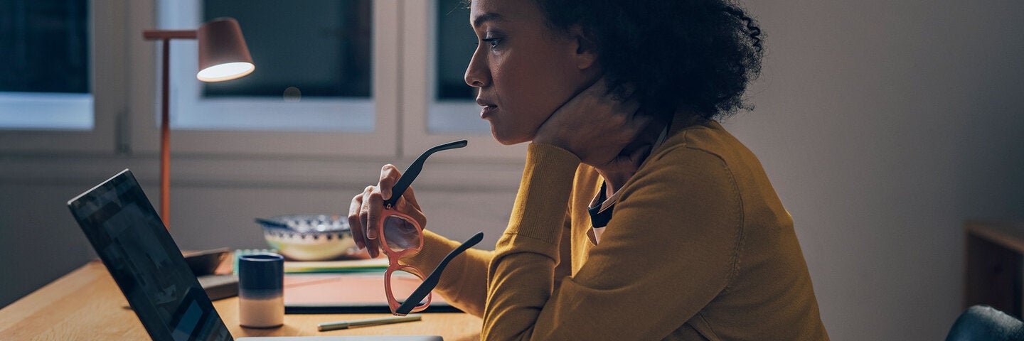 Woman holding glasses analyzing laptop screen