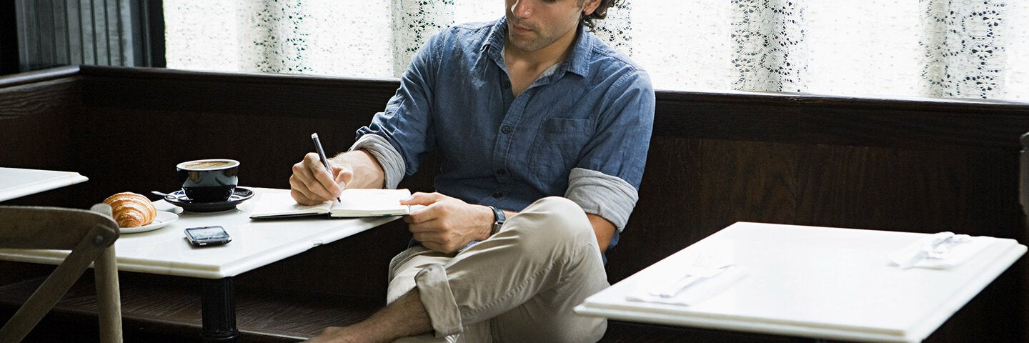 casually dressed man writing in an empty restaurant