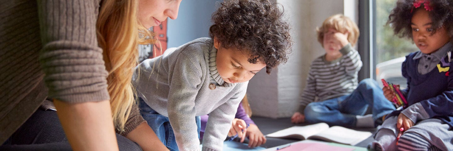 teacher demonstrating art to children