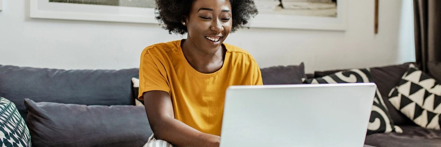 African American female writer smiling at laptop