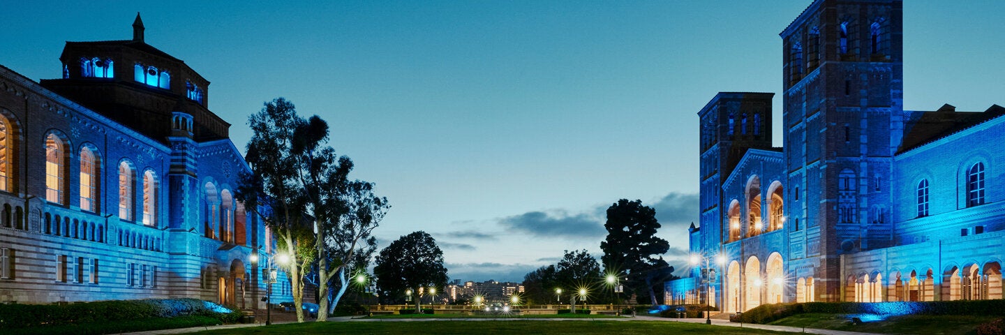 UCLA campus at dusk with Royce Hall and Powell Library illuminated in blue lights