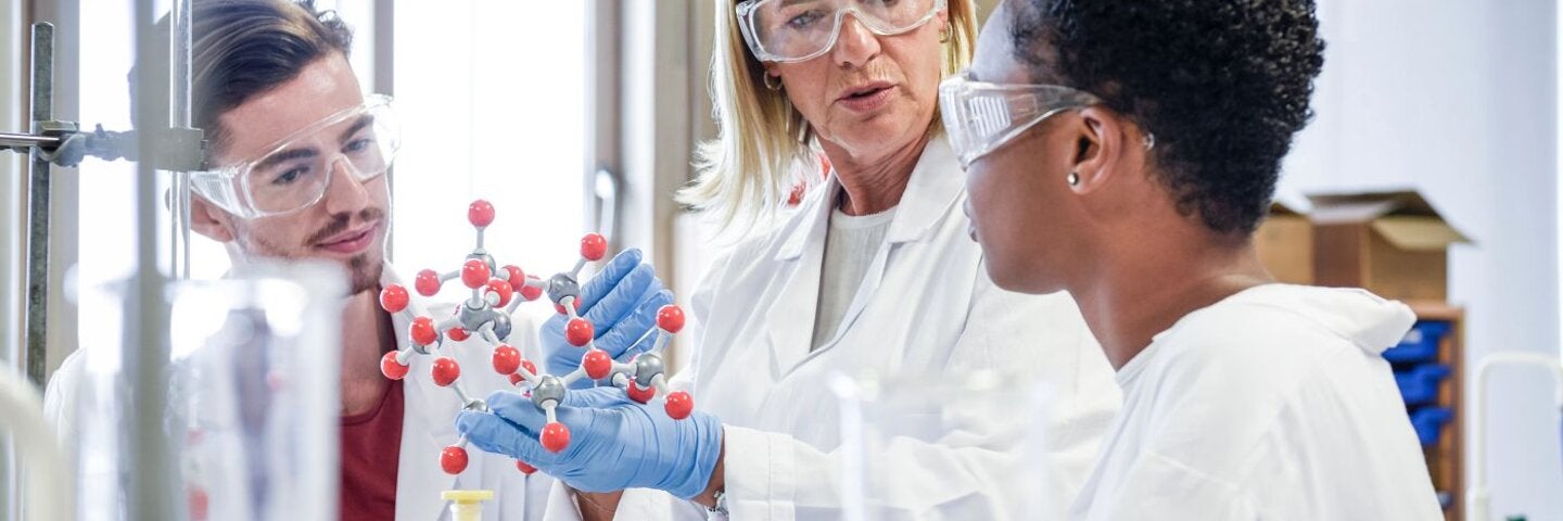 Instructor and students discussing molecular structures in a lab