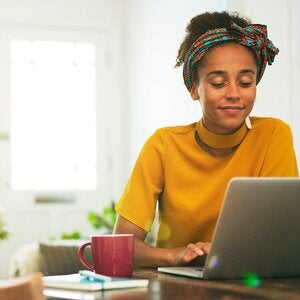 black woman in yellow sweater at laptop