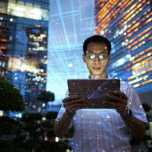 person-reading-tablet-against-a-digital-abstract-background