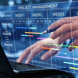 Project manager working on laptop and updating tasks and milestones progress planning with Gantt chart.
