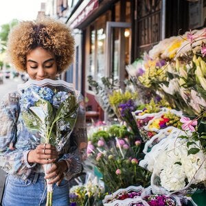 woman smelling hydrangeas outside a flower shop